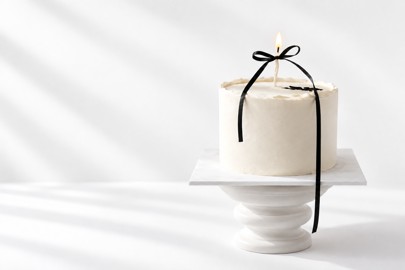 A birthday cake with lit candles on a glass cake stand